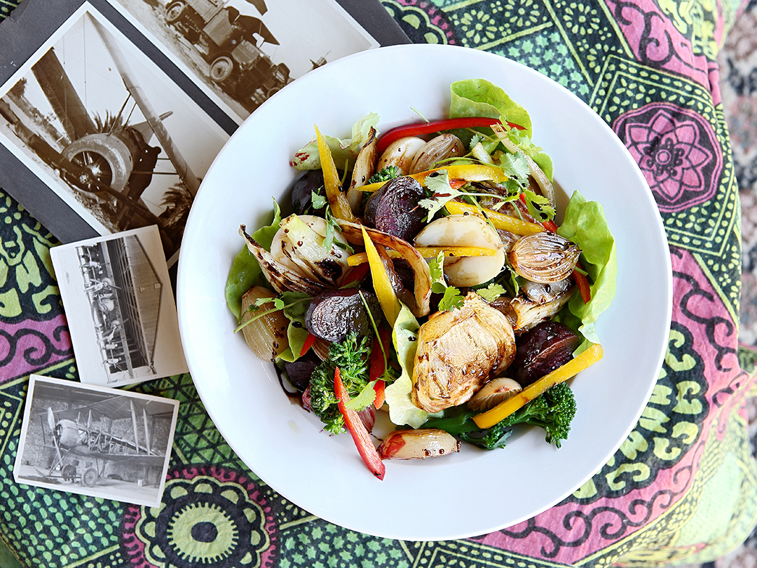 Beautiful salad from local, fresh ingredients on a patterned tablecloth with vintage photographs.