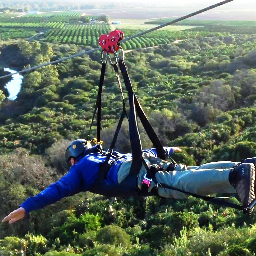 Man zip-lining down a hillside above the citrus groves of the Sundays River Valley.